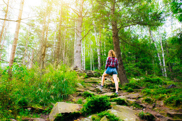 Hipster girl in the mountains. Stylish woman in straw hat and checkered shirt in forest. Wanderlust concept. Travelling and hiking in summer. mysterious wood. Beautiful nature.