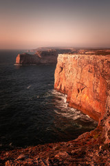 Fototapeta na wymiar High red cliffs around Sao Vicente cape at south-west corner of Portugal, at the Algarve region.