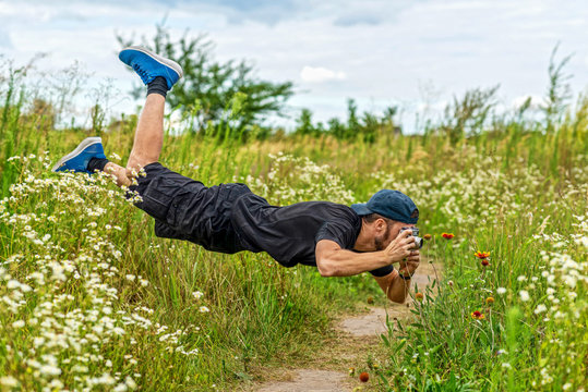 A photographer takes pictures of flowers in flight. The young man levitates in the field.