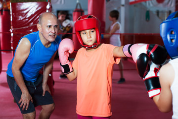 Group of kids practicing with mentor on boxing ring at gym