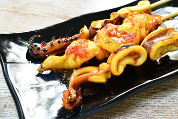 grilled squid dressing spicy sauce stabbing wooden stick on plate