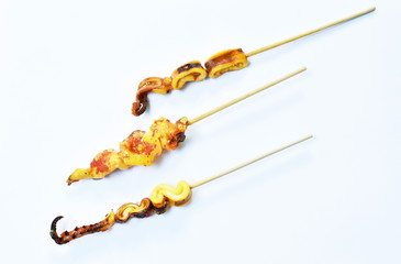 grilled squid dressing spicy sauce stabbing in wooden stick on white background