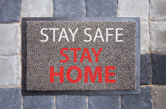Disease avoid spread concept. Home doormat with text: Stay safe, stay home. Home decor with message. - Powered by Adobe