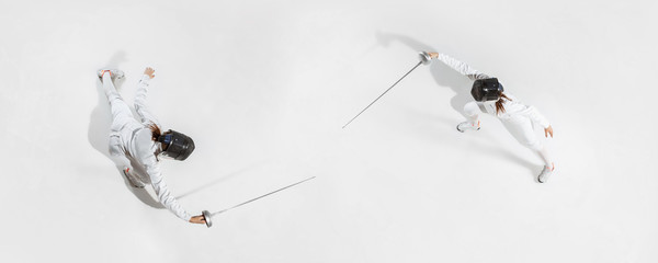 First. Teen girl in fencing costume with sword in hand on white background. Top view. Young female...