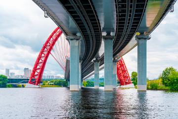 Picturesque red bridge over the river in Moscow, photo taken under the bridge with metal holding beams
