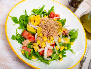 Portion of delicious salad with canned tuna fish, greens, avocado and tomatoes