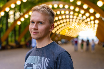  Portrait of a young man with backpack in Sokolniki Park in Moscow under an arch with lanterns - Powered by Adobe