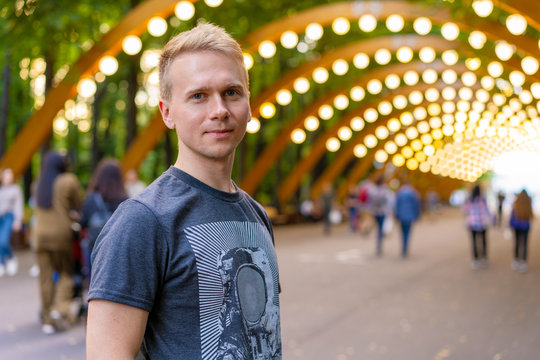  Portrait of a young man with backpack in Sokolniki Park in Moscow under an arch with lanterns