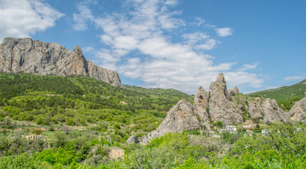 Rocks between green valleys. Road, small houses hidden in the trees. Nice panorama with beautiful clouds and sunny day. Krim