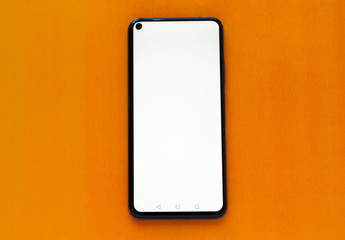 Black smartphone with white blank screen, orange background.Place for text. Perspective view of smartphone mockup with blank white screen