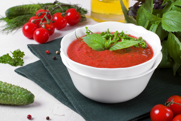 Tomato gazpacho soup in a ceramic bowl topped with basil leaves. Spanish cuisine cold soup