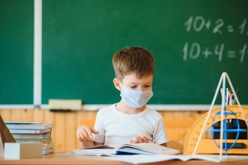 Schoolboy in the classroom in a protective mask. The concept of schooling during the epidemic