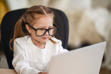 little girl with glasses using the digital concept of e-learning using a laptop.