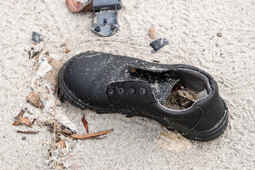 Old discarded leather shoe at beach in Panama City in Panama. Trash in sand. Environmental...