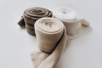 Three rolls of cashmere in different pastel colors with on white background. Selective focus. Close Up view. Blurred background - obrazy, fototapety, plakaty