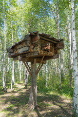 wooden house on high legs in a birch forest. hut standing on chicken legs. Wooden House Fairy Grandmother Yaga.