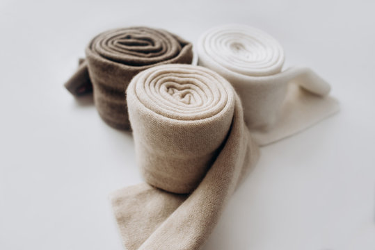 Three rolls of cashmere in different pastel colors with on white background. Selective focus. Close Up view. Blurred background