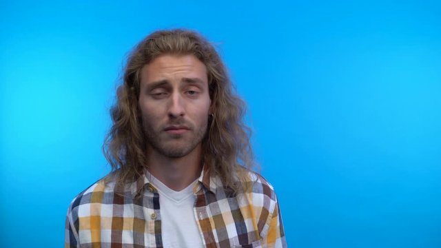 Close up. a hipster man looks at the camera with disgust.