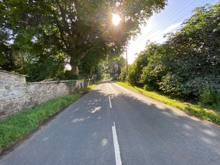 The B6160 road, in West Burton, with dry stone walls and broken sunlight, Leyburn, UK