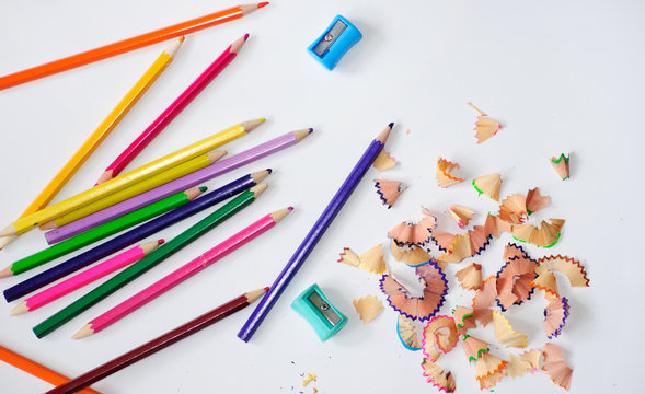 close-up picture of pencil peels  from sharpening,
sharpeners and a colored pencils  on a light bacground.