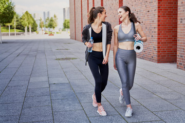 Two laughing athletic women come back from training