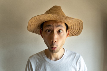 麦わら帽子をかぶった日本人男性が驚いている
