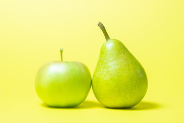 Apple and pear on a yellow background. Fruit is green.