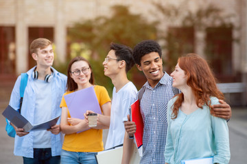Five multiracial students walking together near campus