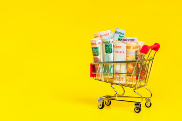 Russian ruble banknotes in shopping cart on yellow background. Copy space for text