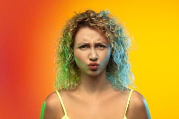 Like a child. Close up caucasian young woman's portrait on gradient studio background in neon. Beautiful female curly model in casual style. Concept of human emotions, facial expression, youth, sales