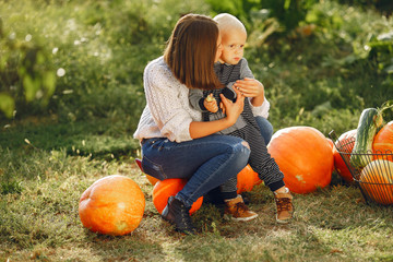 Fototapeta premium Family in a garden. People with pumpkins. Woman in a white sweater