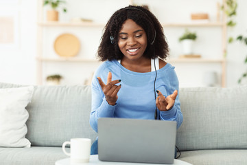 Smiling black woman sitting on couch with headset
