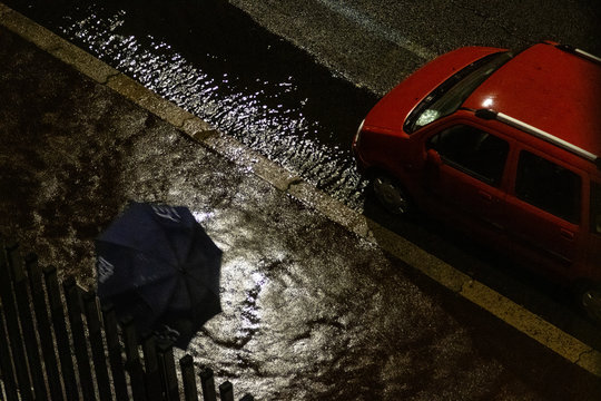 Persona con ombrello e auto con pozzanghera