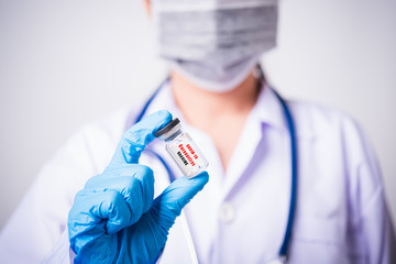 Obraz premium Closeup female woman doctor or scientist in uniform wearing face mask protective in lab use hand finger hold vial vaccine bottle, and on vial vaccine have 