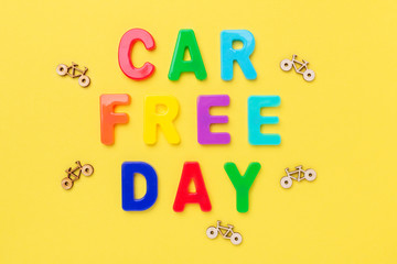 Multicolored text Car Free Day and small bicycles on yellow background. Concept of world car free day on September 22. Top view