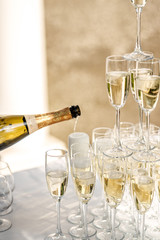 Pouring champagne into wine glasses. Wine glasses in the shape of a pyramid flutes on a wedding.