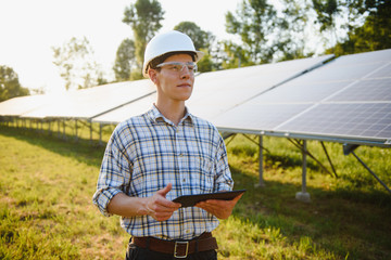 The portrait of a young engineer checks with tablet operation with sun, cleanliness on field of...