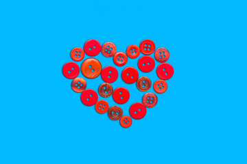 Red buttons are laid out in the form of a heart on a blue background. Valentine's day and birthday card. The view from the top