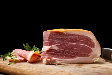 chopped into pieces of prosciutto on a brown wooden board