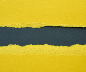 background of layered yellow torn paper with a shadow on a black background