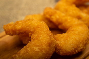 Atlantic prawns fried in batter on a wooden serving Board. Close up.
