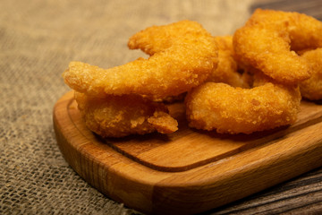 Atlantic prawns fried in batter on a wooden serving Board. Close up.