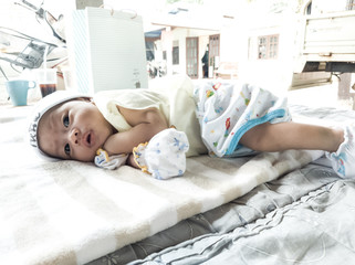 The baby is lying alone on the mattress.
