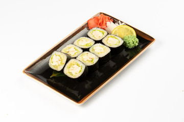 A portion of maki sushi with an assortment of Japanese side dishes in a rectangular ceramic plate on a white plate.