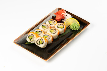 A portion of maki sushi with an assortment of Japanese side dishes in a rectangular ceramic plate on a white plate.