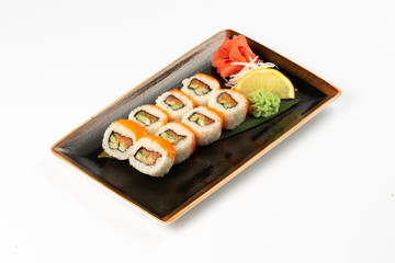 A portion of maki sushi with an assortment of Japanese side dishes in a rectangular ceramic plate on a white plate.