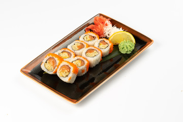 A portion of maki sushi with an assortment of Japanese side dishes in a rectangular ceramic plate on a white plate.