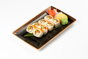 A portion of maki sushi with an assortment of Japanese side dishes in a rectangular ceramic plate on a white plate.