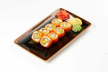 A portion of maki sushi with an assortment of Japanese side dishes in a rectangular ceramic plate on a white plate.