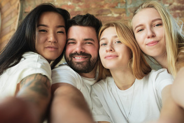 Taking selfie together. Group of adorable multiethnic friends having fun at home. Copyspace. Diversity, inclusion, friendship and love concept. Different nationalities united with sincere emotions.
